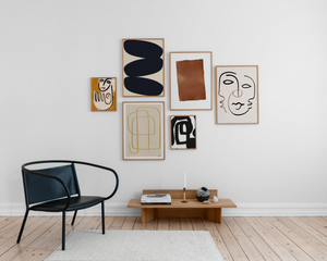 Wand mit Kunstwerken und schwarzem Stuhl