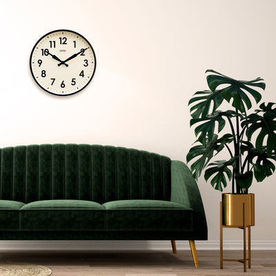 Wanduhr schwarz groß über Sofa und Pflanze