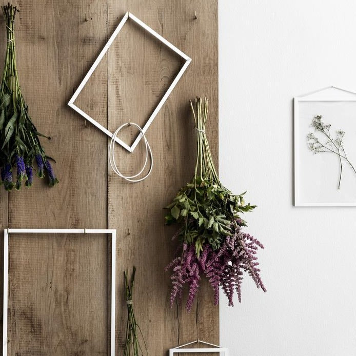 weiße Rahmen an Holzwand mit Blumen