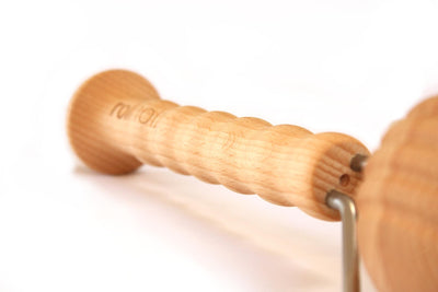 Der Griff eines Faszienrollers von rollholz mit Einkerbungen für die Finger vor weißem Hintergrund