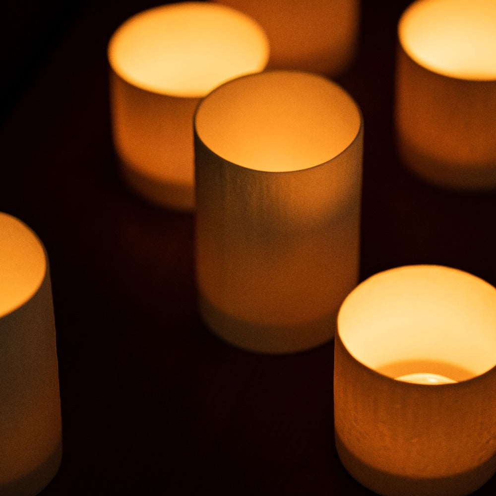 verschieden große Windlichter mit angezündeten Kerzen darin von oben